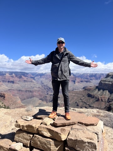 Dr. Walsh standing on the edge of the Grand Canyon with arms open